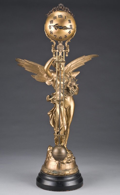 Ansonia "Gloria" swing arm mystery clock modeled a: Ansonia "Gloria" swing arm mystery clock modeled as a patinated spelter figure of the Goddess Gloria clutching a harp in her left arm, her right arm held aloft supporting the swinging ball armature. R