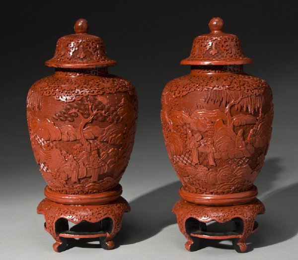 Pr. Chinese carved cinnabar lacquered ginger jars: Pr. Chinese carved cinnabar lacquered ginger jars carved to depict figures in a landscape raised on cinnabar bases. With stand: 15"H, Circa - 19th C.