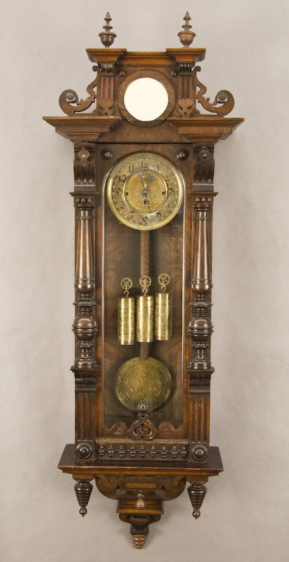 3-Weight Vienna regulator walnut wall clock: with inset mirror in the crest, the door with turned half columns enclosing a typical 3-weight movement striking on two coiled gongs, with engraved dial, pendulum bob and weights. 53"H x 18"W x 9"D, C