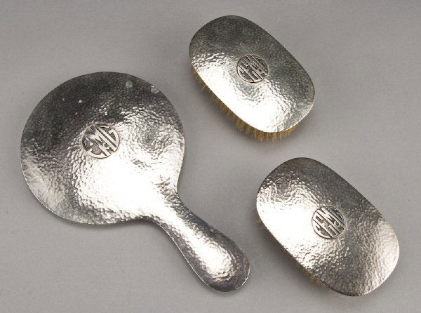 3 Pc. Arts and Crafts silver grooming set: by Lebolt, in hammered sterling silver with applied monogram having a hand mirror and a pair of brushes, the mirror monogrammed "EGMc", the brushes, "FEGMc". Stamped, "Lebolt Sterling 4003" and "Lebol