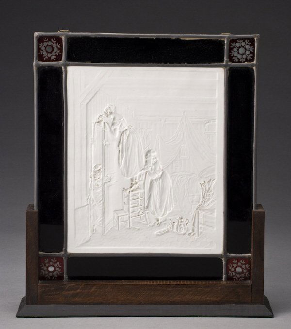 KPM lithopane and leaded glass plaque,: depicting an interior scene with two young girls pouring water from a water jug on an unsuspecting visitor. Impressed KPM with scepter mark with various impressed and incised marks. Surrounded by pane