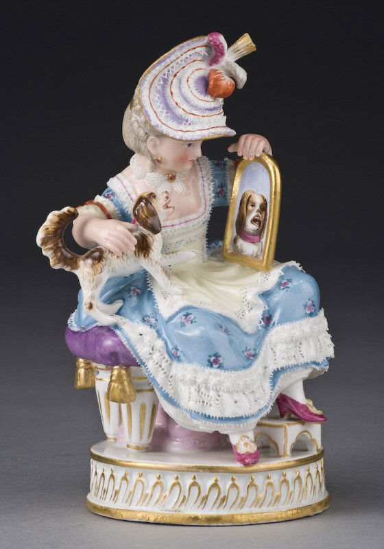 Meissen figural group of a lady with dog: depicting a young lady seated holding a dog and looking glass, on a round socle, after the model by Acier. Blue crossed swords mark under the glaze, incised: "F50", and "59" in black. 5.75"H, Circa -