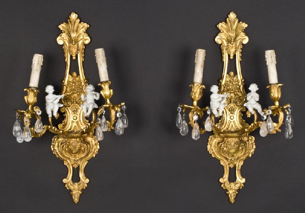 Pr. Louis XV style dore bronze and bisque sconces: with two scroll arms mounted with bisque putti playing instruments and decorated with drop rock crystals. 24"H x 13"W x 7"D, Circa - 20th C.