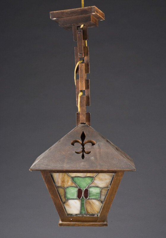 Attributed to Brooks Arts and Crafts hanging lamp,: the wood frame carved with pierced fleur-de-lis above four lead paned slag glass panels, with holly designs. Unmarked. 25"H- to ceiling plaque, 12.25" Sq., Circa - First half 20th C.
