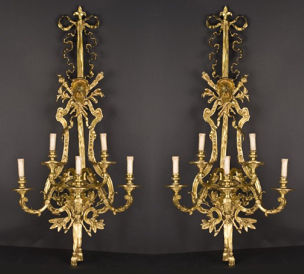 Pr. French Regence style dore bronze sconces: with ribbon tops centered with quill and torch details, issuing 5 scrolled acanthus covered arms, above central masks and finished in tassels. 47"H x 22.5"W x 14"D, Circa - 20th C.