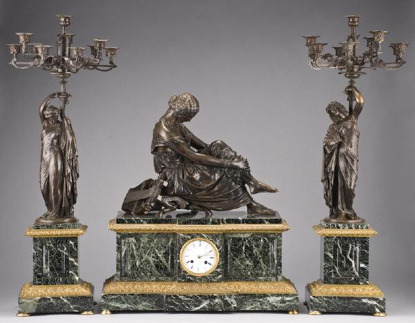 3pc. Napoleon III clock set by Susse Freres: the figures sculpted after Jean-Jacques Pradier. The clock surmounted by a patinated bronze figure modeled as Sappho seated, the white enamel dial marked, "Susse Freres A Paris"; with a pair of ten li