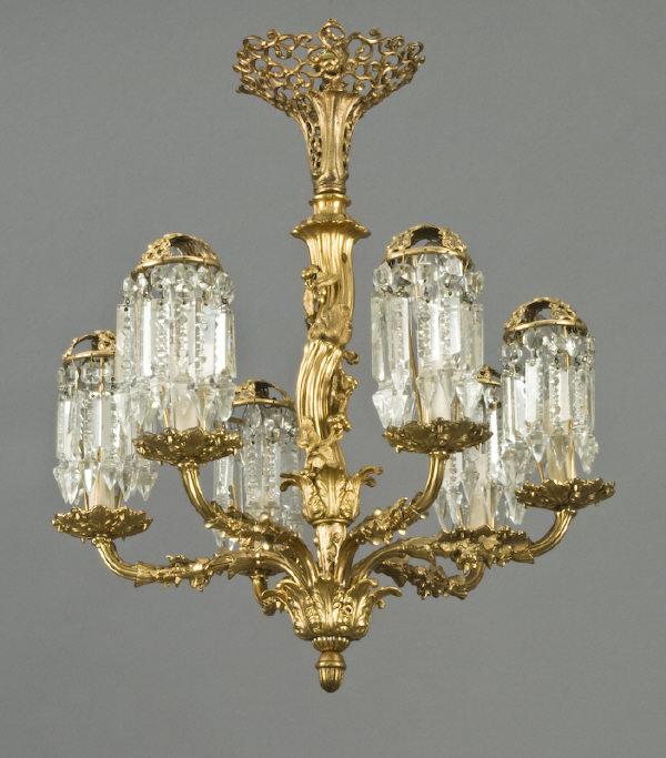 French dore bronze six light chandelier,: the shaft formed as a twisted grapevine, issuing grapevine wrapped scrolling arms, the candle cups supporting pierced bronze shades, suspended with faceted crystals. Electrified. 22"H x 19" Dia., Circ