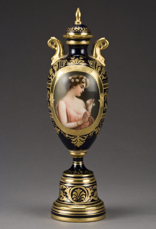 Vienna style lidded porcelain urn signed, "Wagner": the whole with raised gilt detailing, hand painted reserve depicting Marguerite signed, "Wagner". The underside with an over glaze beehive mark also inscribed, "Marguerite depose". 11"H, Circa - Late 