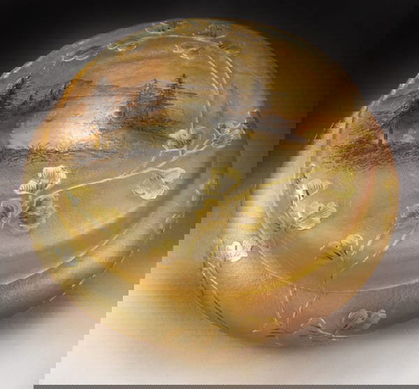 Daum Nancy French cameo covered dresser box,: ovoid form in rainbow crimson and opalescent green decorated with a gray enameled pictorial of a tree lined mountain stream, the picture is framed with random stemmed gilt cameo flowers, signed, "Daum