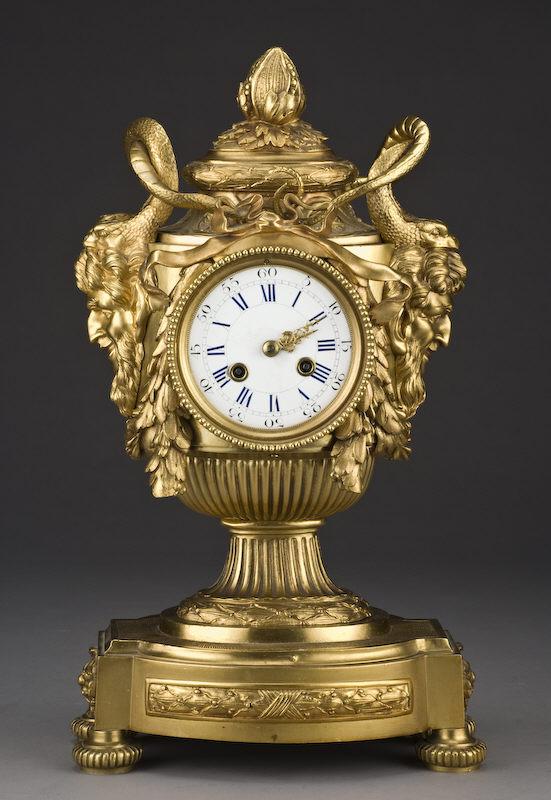 Louis XVI style Japy Freres dore bronze clock,: the enamel dial marked with Roman and Arabic numerals, draped with ribbons and swags, the handles formed by grotesques and serpents, the gadrooned standard and plinth adorned with laurel. French brass
