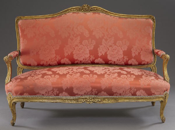 Louis XV style gilt wood settee,: Louis XV style gilt wood settee, the back rail with floral crest, and having fluted and scrolled padded arms and upholstered seat, resting on floret carved cabriole legs. 40" H x 57.75" W x 28.25" D, 