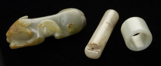 3 Pcs. Chinese Qing carved jade including: (1) arc: 3 Pcs. Chinese Qing carved jade including: (1) archer's ring, 1" Dia.; (1) dog, 3.75"L; (1) jadeite feather holder, 3.25"L.
