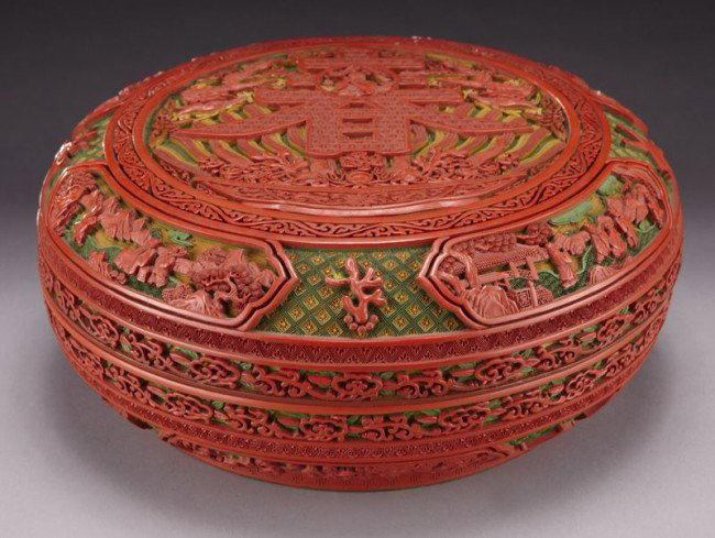 Chinese carved cinnabar penghe box, carved to depi: Chinese carved cinnabar penghe box, carved to depict the God of Longevity, the character for Spring, figures in a landscape and lucky symbols. Six character mark on base. 5"H x 12" Dia., Circa - 20th