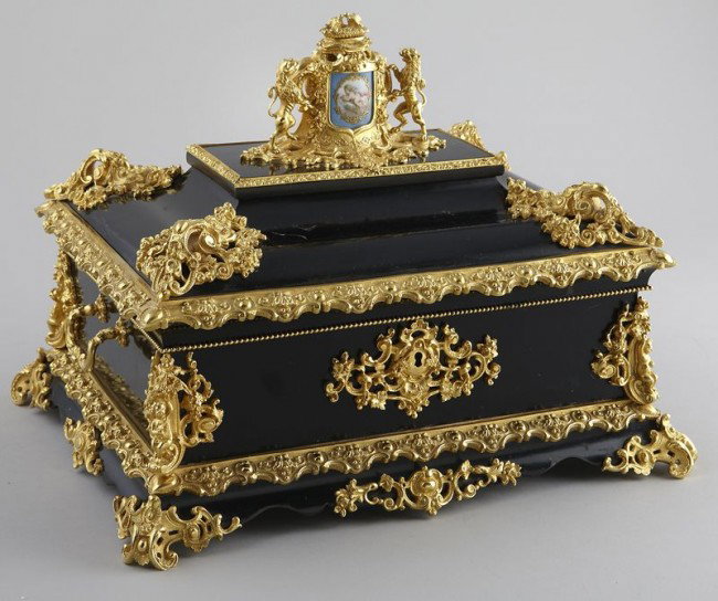 Napoleon III style dore bronze mounted casket: of ebonized wood, the ornate finial with inset porcelain plaque depicting a putti. 12.75"H x 16.25"W x 13"D, Circa - Early 20th C.