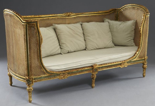 Italian painted and parcel gilt caned settee,: the gilt wood doubled caned frame with laurel detailing, the seat rail with tied ribbon motif, resting on carved fluted legs. 41.5"H x 79.5"W x 49.5"D, Circa - 20th C.