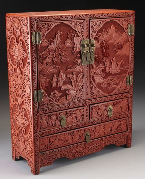 Chinese carved cinnabar table cabinet: depicting figures in a landscape, having a pair of doors, over two short drawers and one long drawer. 19.25"H x 16"W x 6"D, Circa - 20th C.