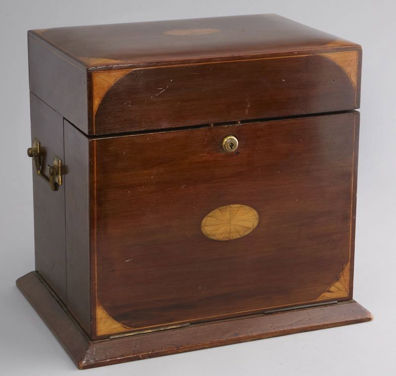 Edwardian decanter set having a single drawer,: the interior with a mirrored lid and fitted with three cut glass lidded decanters, a gilded tray and an inlaid cribbage board. 14"H x 15.5"W x 11.25"D, Circa - 1900.