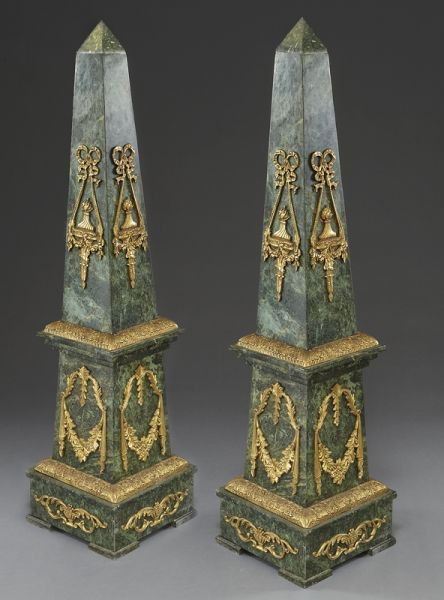 Pr. Large marble obelisks with bronze mounts,: the upper section decorated with bronze mounts resembling torchieres, the central section with floral swags, the base with acanthus draped urns. 56"H x 13.75" Sq., Circa - 20th C.
