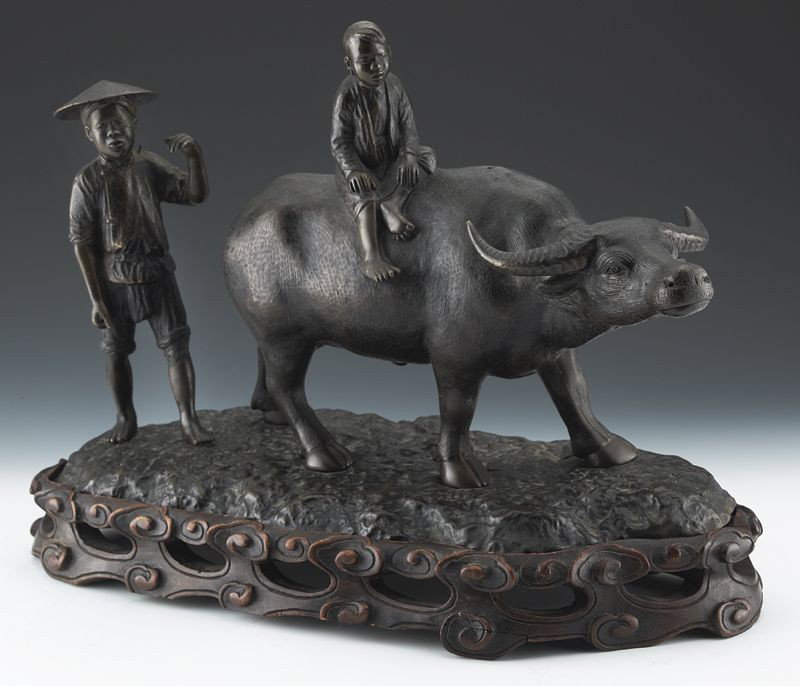 Vietnamese cast bronze figural group: depicting two boys riding a water buffalo, raised on a hard wood base. Bronze: 11.5"H x 18"W, Circa - 19th C.