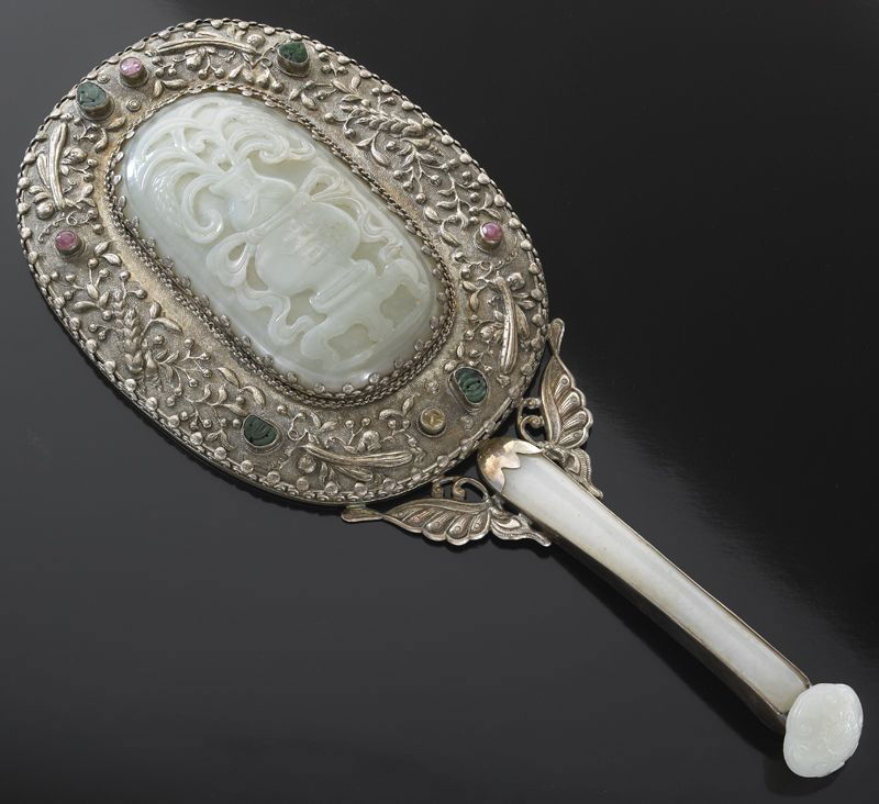 Chinese Qing silver mounted jade mirror,: the jade plaque depicting flowers and vases 4.25"H x 2.5"W, the jade hair pin handle in ruyi shape, 5"L, the mirror mounted with jadeite and tourmaline. Overall: 11.5"H, Circa - 19th C.