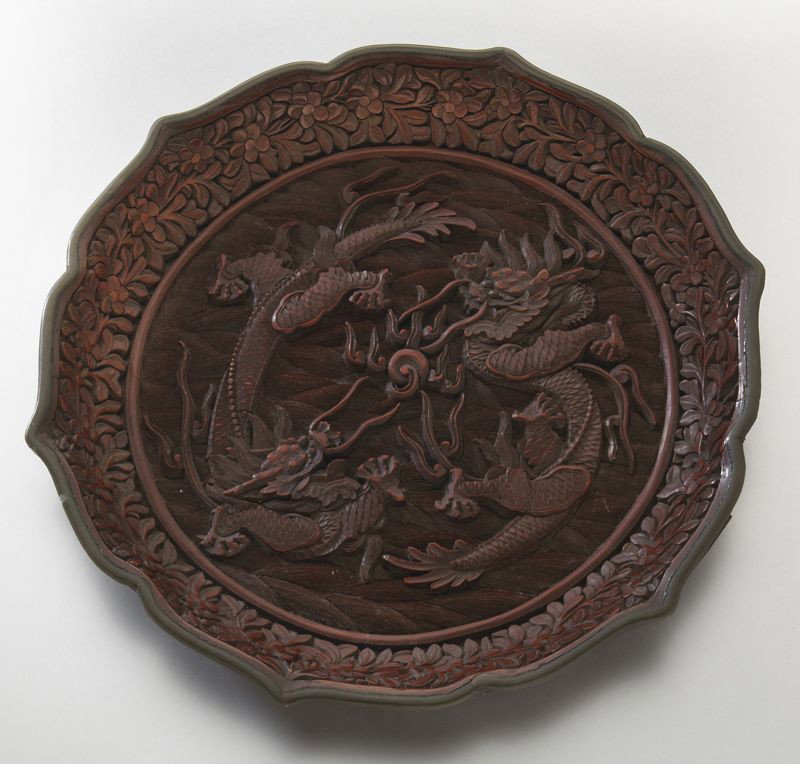 Chinese Qing carved cinnabar dish: depicting two dragons chasing the flaming pearl. Spurious six character Qianlong mark on base. 8" Dia., Circa - 18th - 19th C.