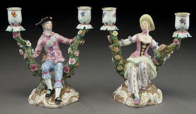 Pr. Meissen porcelain figural candlesticks: modeled as a gentleman and a lady each seated in a naturalistically modeled rocky outcropping, the two candle arms formed as tree branches with applied flowers. Cross swords mark in blue under glaze,