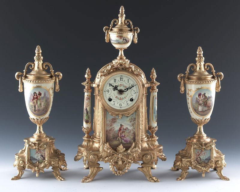 3 Pc. Louis XVI style porcelain and bronze clock: garniture set, the urn mounted clock with a decorated dial and Arabic numerals, the inset porcelain panels depicting gallante scenes, having a German time strike movement; 16.75''H x 9''W. With a pair