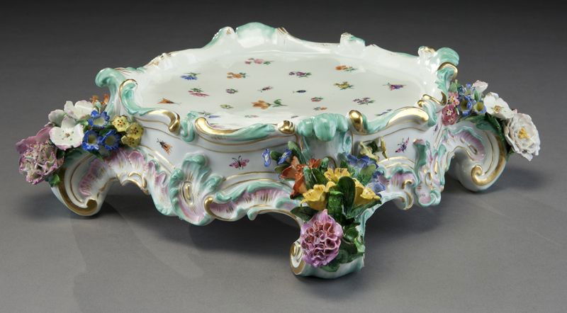Meissen porcelain plateau: with gilt details raised on rocaille feet with hand painted floral detail and applied floral decoration. Crossed swords mark in blue under glaze with incised marks, "2772". 3.5"H x 14"W, Circa - Late