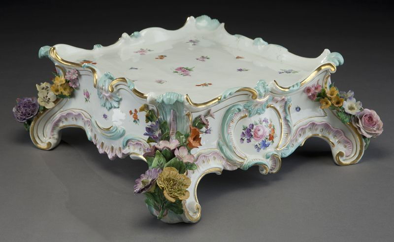Meissen porcelain plateau: with gilt details raised on rocaille feet with hand painted floral detail and applied floral decoration. Crossed swords mark in blue under glaze with additional incised and painted marks. 5"H x 18"W,