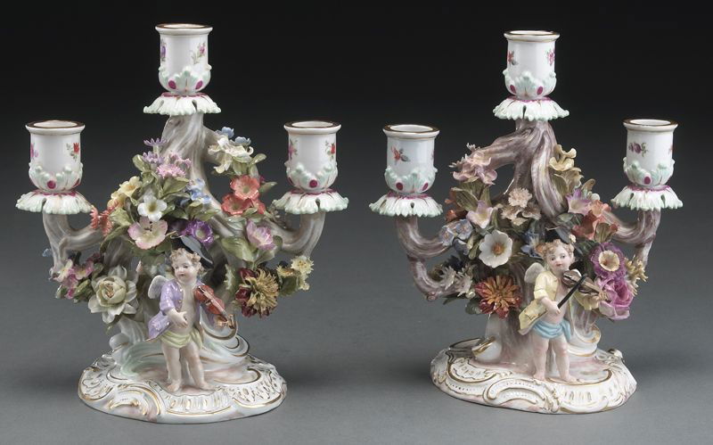 Pr. Meissen porcelain three light candelabras: covered in applied floral decoration, accented by a male putto playing violin on one side and a female putto dancing on the other. Cross swords mark in blue under glaze, as well as impressed and incis