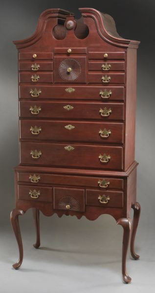 American Chippendale cherry highboy in two parts,: the upper with broken arch pediment over eight short drawers, the center having a carved medallion, above four graduated full size drawers; the lower section with one long drawer and three short drawe