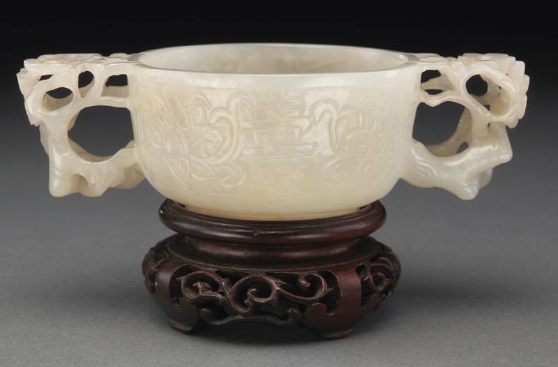 Chinese Ming carved jade libation cup,: with two handles carved to depict lotus and plums, with a longevity character. 1.75"H x 5.25"W, Circa - 16th C.