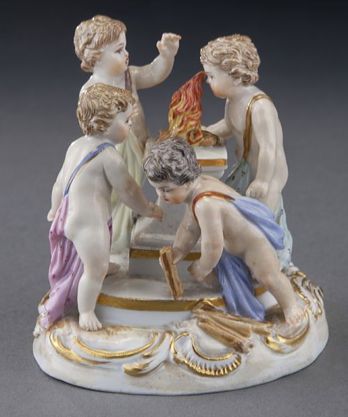 Meissen porcelain figural group of four putti: Meissen porcelain figural group of four putti around a fire burning on a plinth, on an oval gilt decorated base. Cross swords mark in blue under glaze, as well as impressed and incised numerals. 3"H x