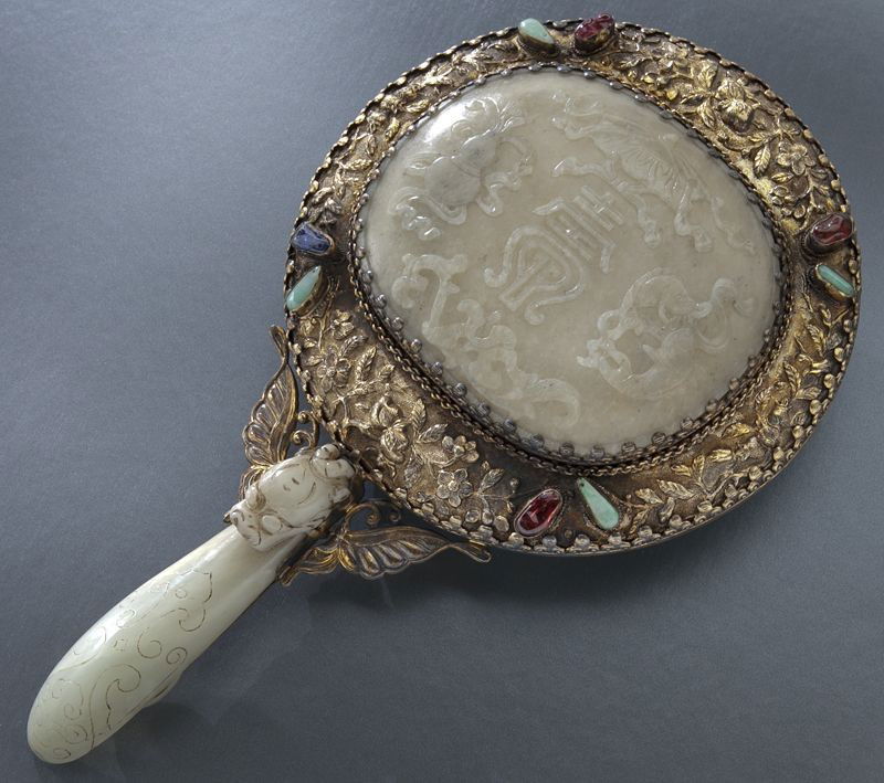Chinese silver mounted jade mirror: Chinese silver mounted jade mirror depicting lucky symbols, the handle a carved jade buckle depicting a dragon, handle stamped, "Silver". 10.5"H, Circa - 19th C.