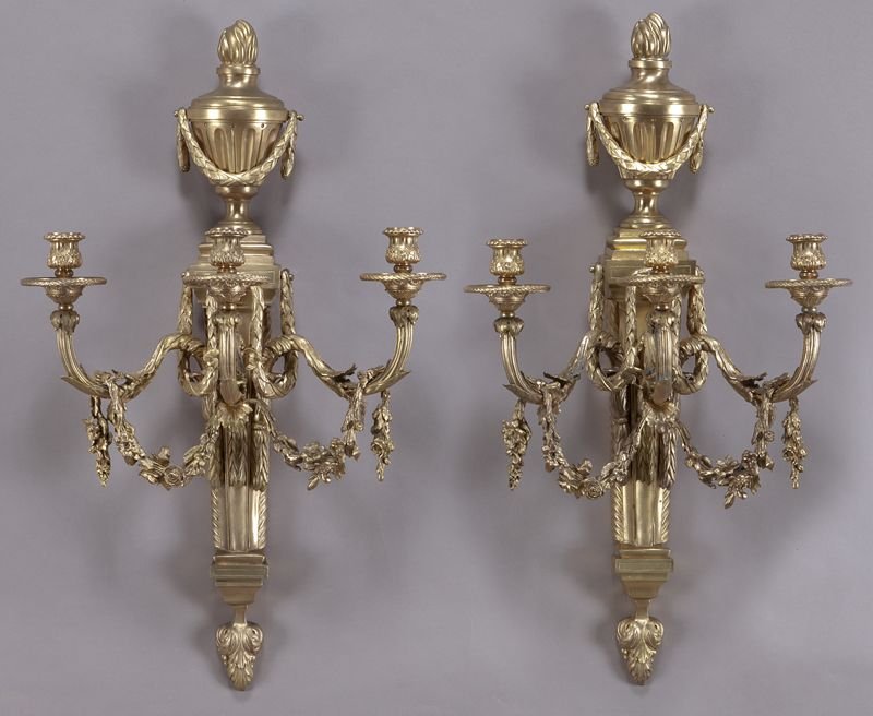 Pr. Regence style gilt bronze sconces,: Pr. Regence style gilt bronze sconces, each three-light sconce surmounted by an urn finial, the acanthine and fluted arms draped in floral garland, having a tapered column support ending in acanthus l