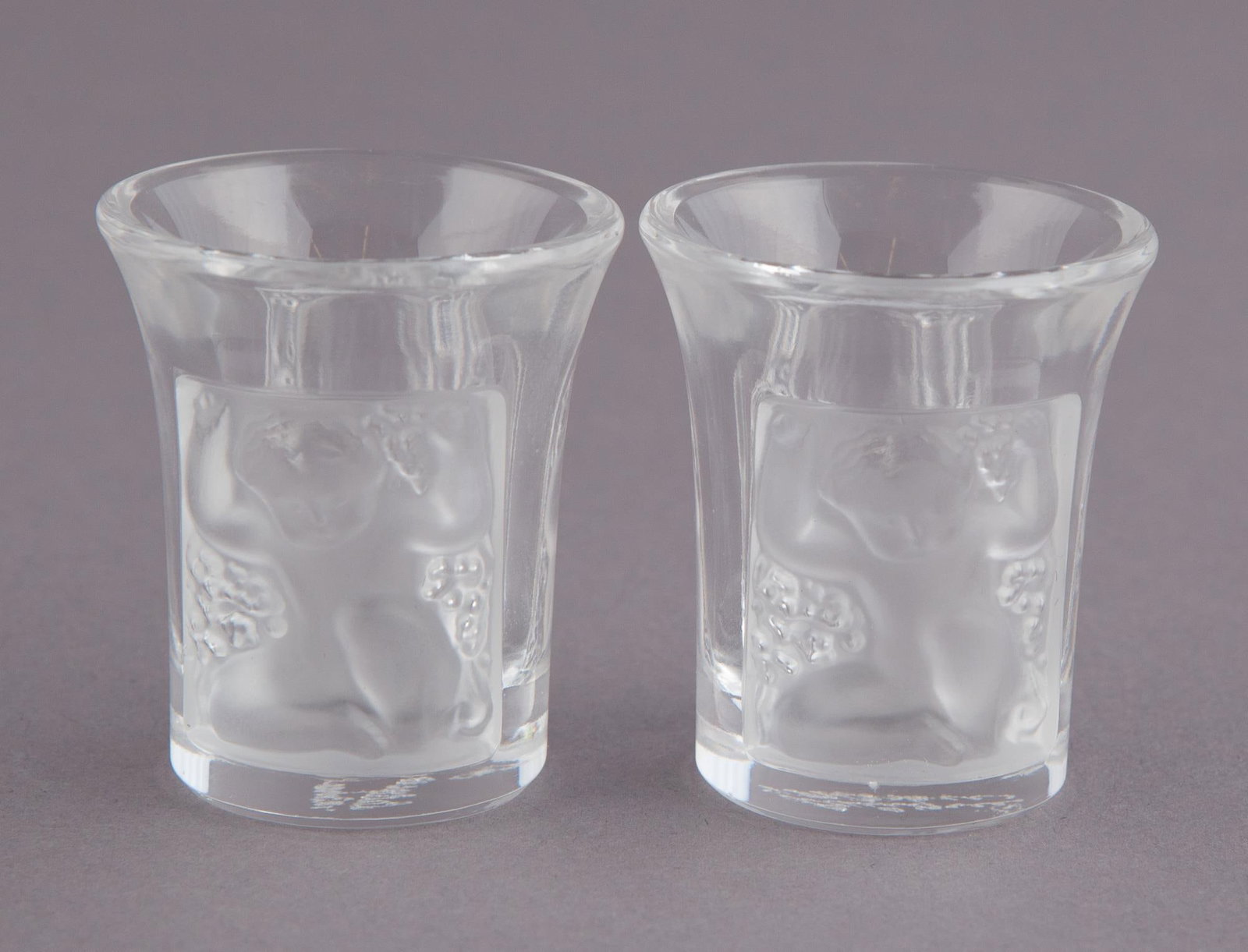 Pair of Lalique Cordials: Beautiful pair of miniature Lalique Cordials with Les Enfants motif. H 1.75 x W 1.70 in H 1.75 x W 1.70 in