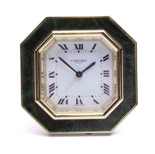 Cartier Travel Clock: Gold Tone with deep green enamel frame. White dial with black enamel roman numerals. Manual wind. Signed Cartier Paris on the back. Measuring H 3.25 W 3.35 in