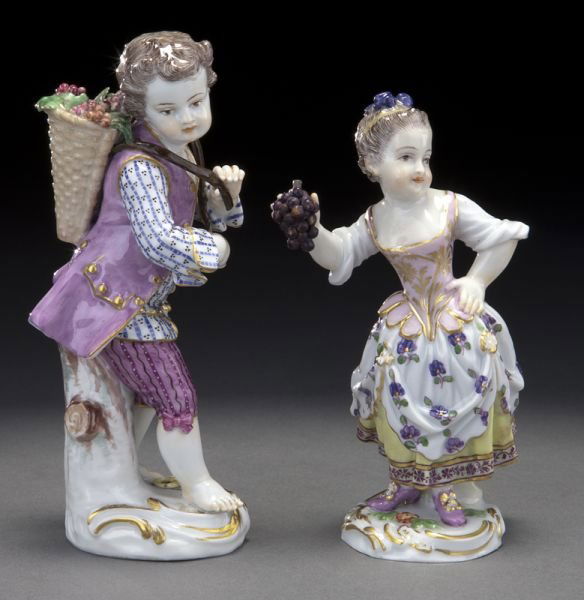 Pr. Meissen porcelain figures of a boy and a girl,: Pr. Meissen porcelain figures of a boy and a girl, the boy carrying a basket of grapes, the girl holding a bunch of grapes, both on circular rocaille bases. Cross swords mark in blue under glaze, as w