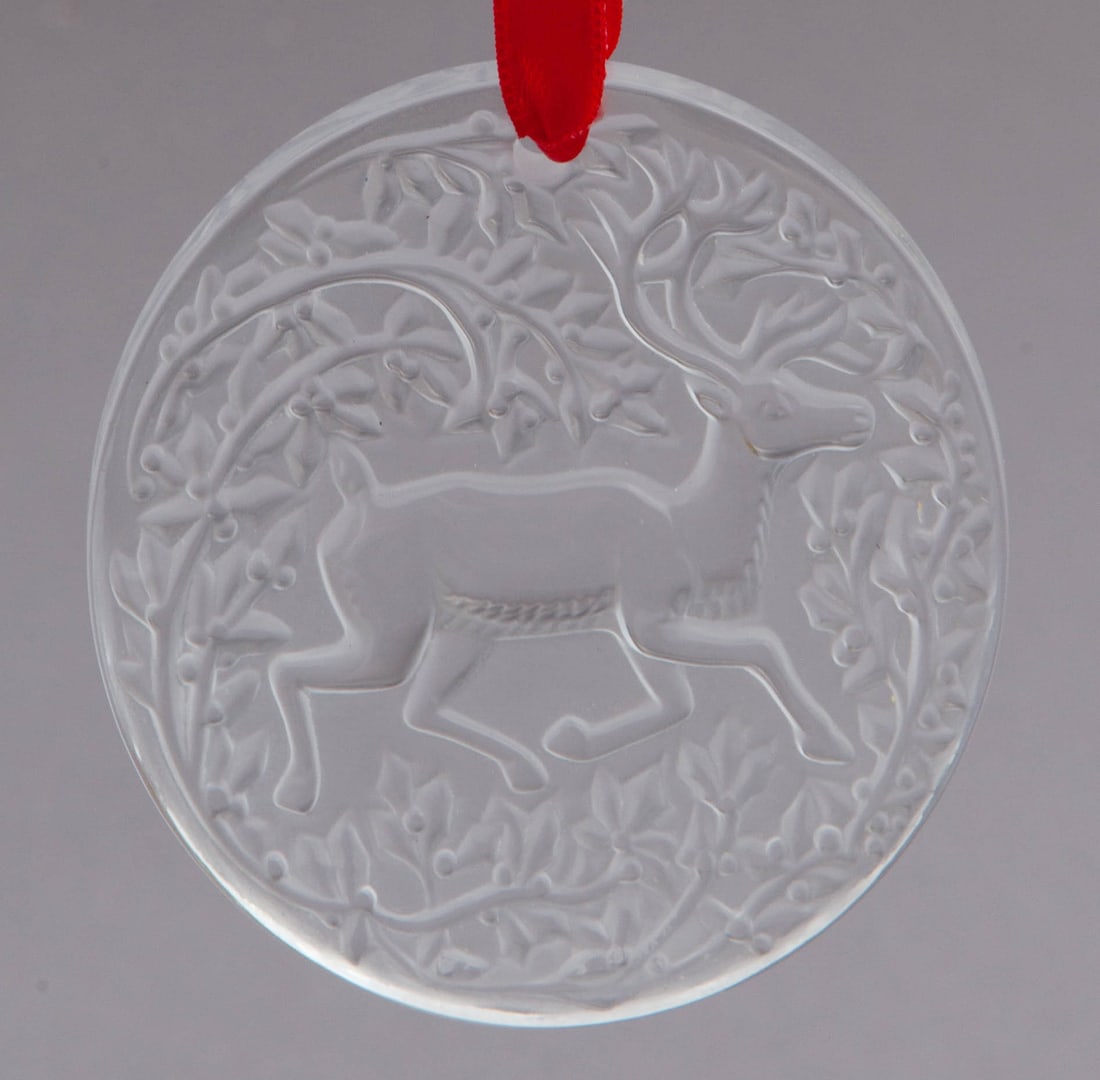 Lalique Seasonal Ornament: Lalique Christmas 1997 ornament, Clear Reindeer Crystal with red ribbon. With original box. Etched Lalique France on verso. Measuring D 2.75 in Box measuring 3 x 3 in No reserve