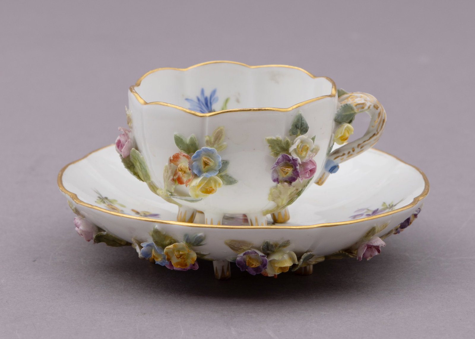 19th Century Meissen Cup and Saucer with Applied and Painted Flowers: Delicate Meissen demitasse and saucer with painted and applied porcelain flowers throughout. Marked with Meissen setter on the underside Cup: D 1.5 x W2.5 inches. Saucer H 1 x W 4 inches Condition: Sm
