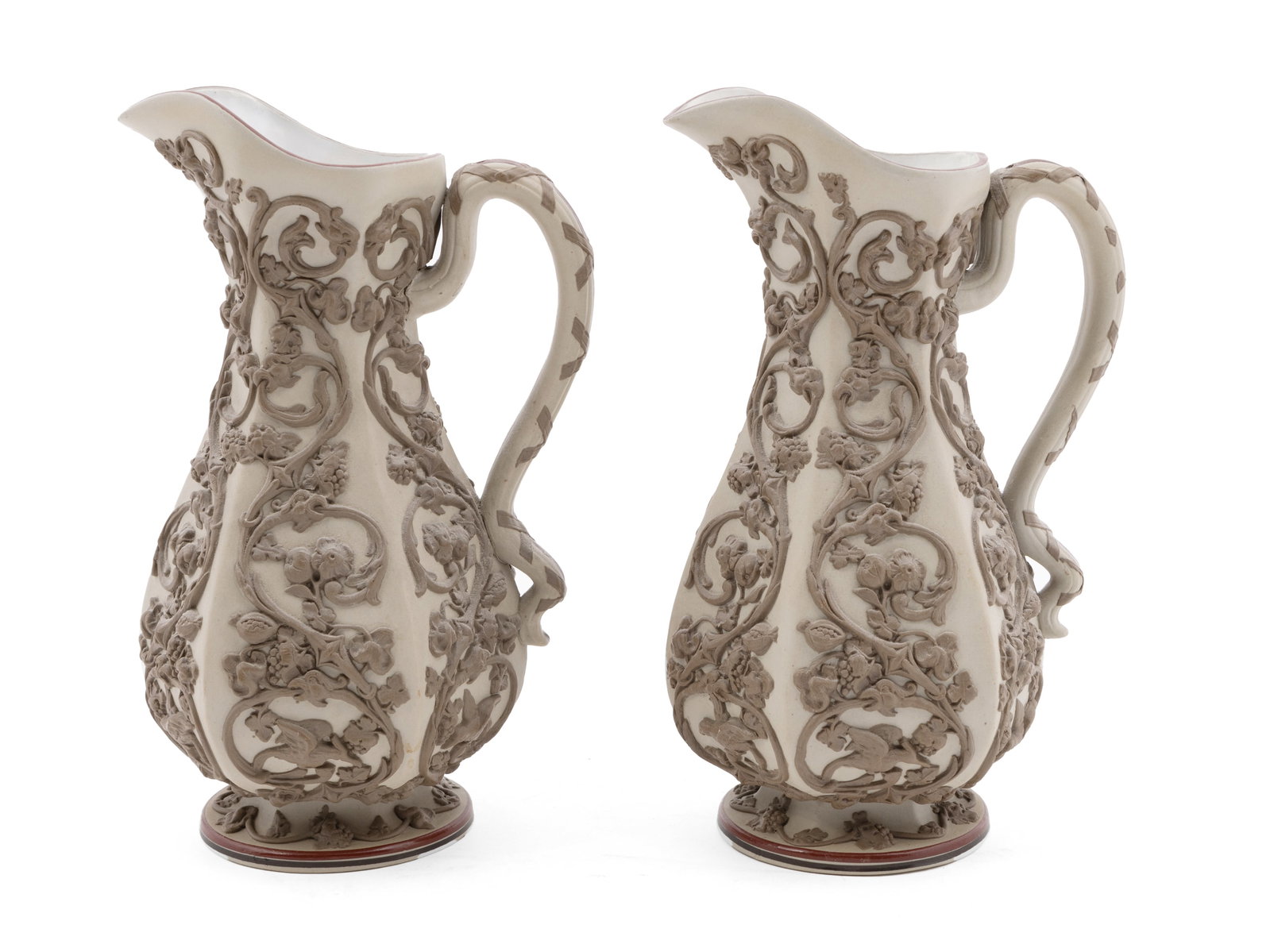 Pair of German Villeroy & Boch Mettlach Bisque Urns: Stunning pair of German Villeroy and Boch urns with intricate vine patterns and red enamel trim. Marked with coat of arms on underside. Measuring H 10.5 W 7 D 4.5 inches Condition: some lo