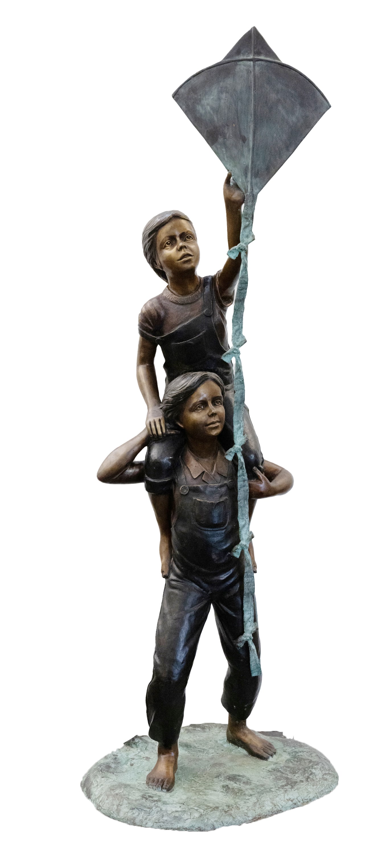 Bronze Cast Boy and Girl with Kite Statue: A stunning statue composed of a bronze cast depicting a boy holding a girl on his shoulders. The girl is holding a kite. They are both dressed in overalls and have bare feet. There is a signature pres