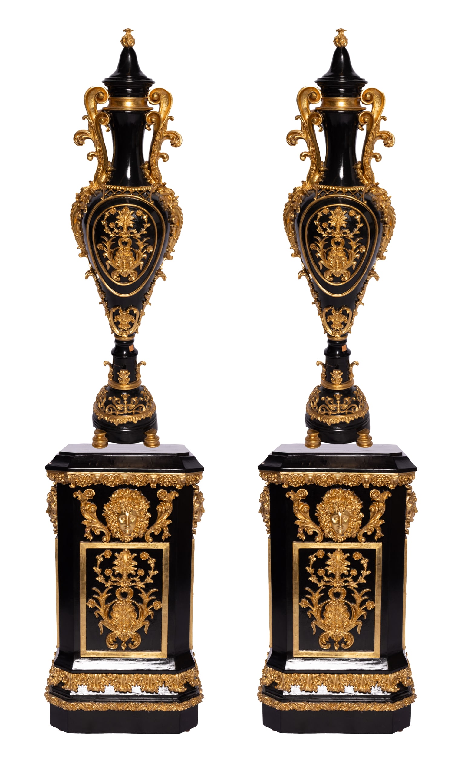 A Pair of Heavily Carved Wooden French-Style Black Vases and Pedestals: Heavily carved black wooden vases and pedestals in French style. These are heavily gilt decorated with filigree and floral motifs. The lids are removable with a twisted finial atop them. The pedestals