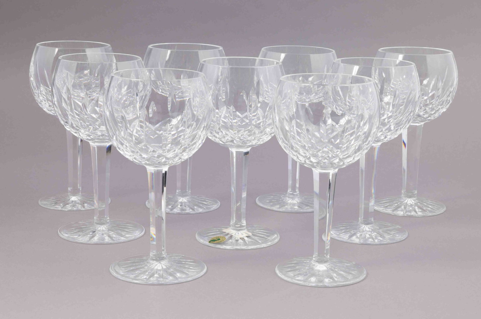 Set of Nine Waterford Crystal Wine Glasses: A set of nine Waterford crystal wine glasses with a faceted stem and base. They all have the Waterford maker's mark on the underside. They measure H 7.75 W 3.5 D 3.5 inches. Condition: all in go