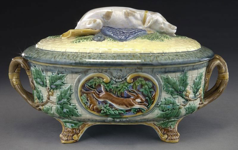 Minton Majolica game pie dish with hunting dog: Minton Majolica game pie dish with hunting dog resting on a rifle and possibles to the lid, the dish of oval form with basket weave ground decorated with oak leaves, a pheasant and a rabbit to the res