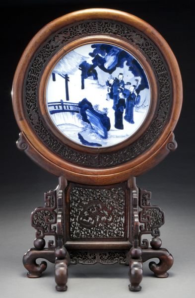 Chinese Qing blue and white porcelain plaque: Chinese Qing blue and white porcelain plaque mounted as a table screen, depicting figures in a landscape. Porcelain: 9.25" Dia.; Overall: 24.5"H, Circa - 19th C.