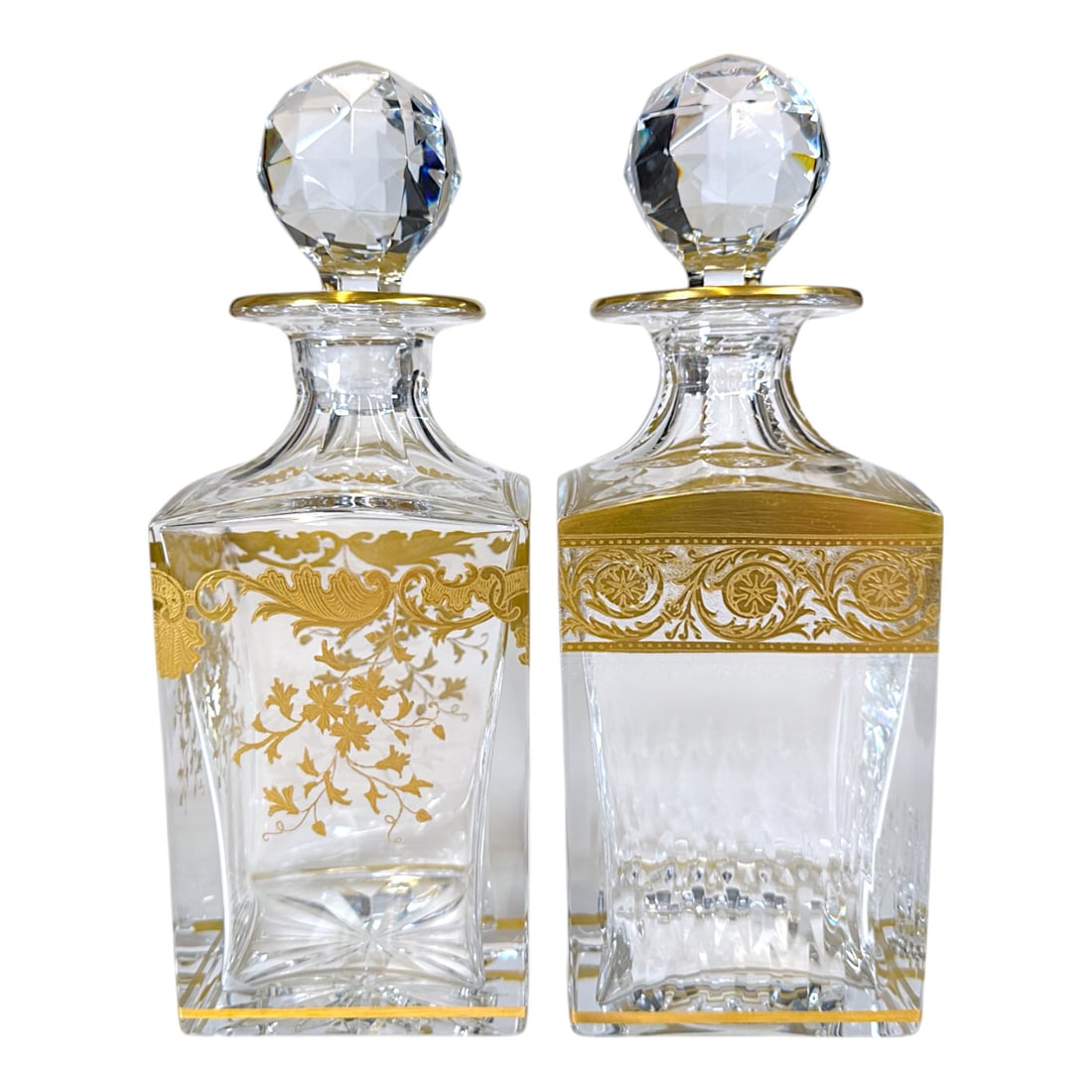 Pair of St. Louis Blown Glass & Gilt Decanters: A stunning pair of St. Louis blown glass decanters. Faceted stoppers with gilt decoration. Signed in acid stamp on the underside base. Measuring: H 10 x W 3.5 x D 3.5 inches Condition: Some interior r
