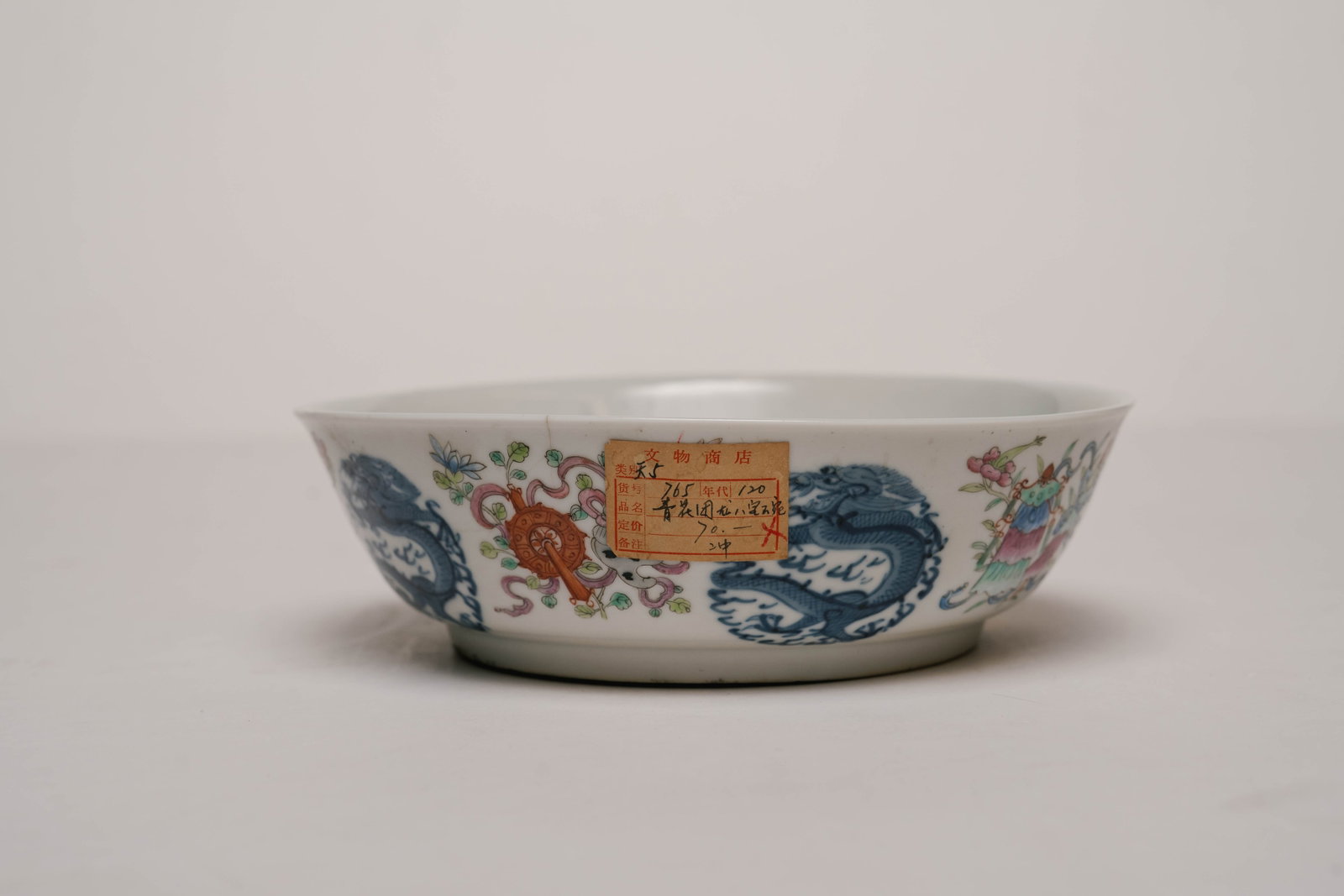 Antique Chinese Bowl with Decorated Dragon Motif: This antique Chinese bowl is decorated with five blue and white dragons on the outside, with multicolored traditional Chinese symbols. The underside features some markings that may indicate the maker 