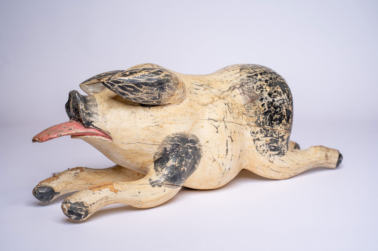 Vintage Folk Art Wooden Painted Pig: A wonderful vintage wooden, hand-painted pig. White with black spots and a pink tongue. Dimensions: H 9 x W 25 x D 8 inches Condition: Tail is missing leading to a hole in the rear with a diamet