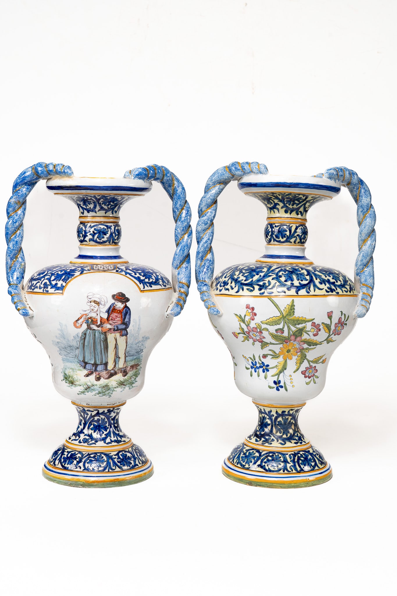 Pair of French Faience Desvres Urns with Handles: Pair of French Faience Desvres Urns with Handles. Painted urns depicting a Breton man and woman together and two Breton men playing instruments. Both urns have painted floral and leaf designs and hand